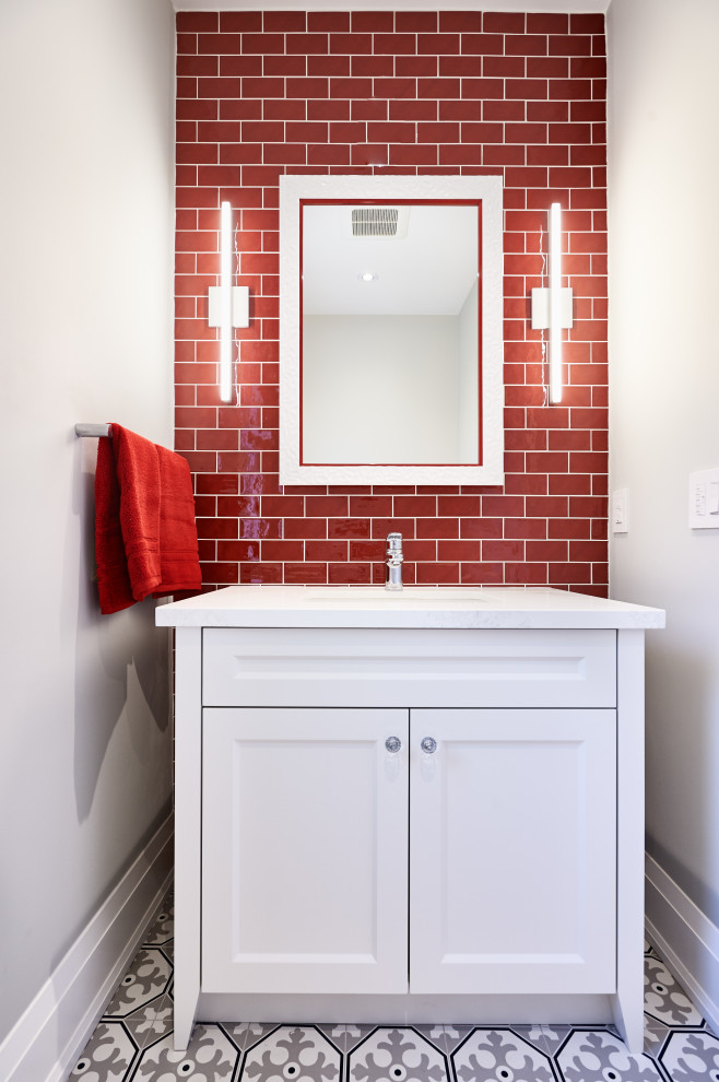 This is an example of a mid-sized transitional powder room in Toronto with recessed-panel cabinets, white cabinets, red tile, grey walls, an undermount sink, multi-coloured floor, white benchtops and a built-in vanity.