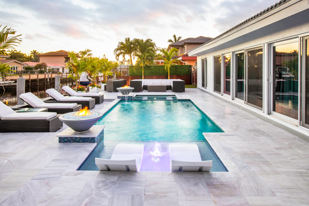 Inspiration for a mid-sized modern backyard rectangular lap pool in Miami with a water feature.