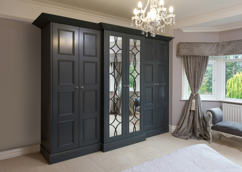 This is an example of a large traditional gender-neutral built-in wardrobe in Other with grey cabinets, carpet and recessed-panel cabinets.