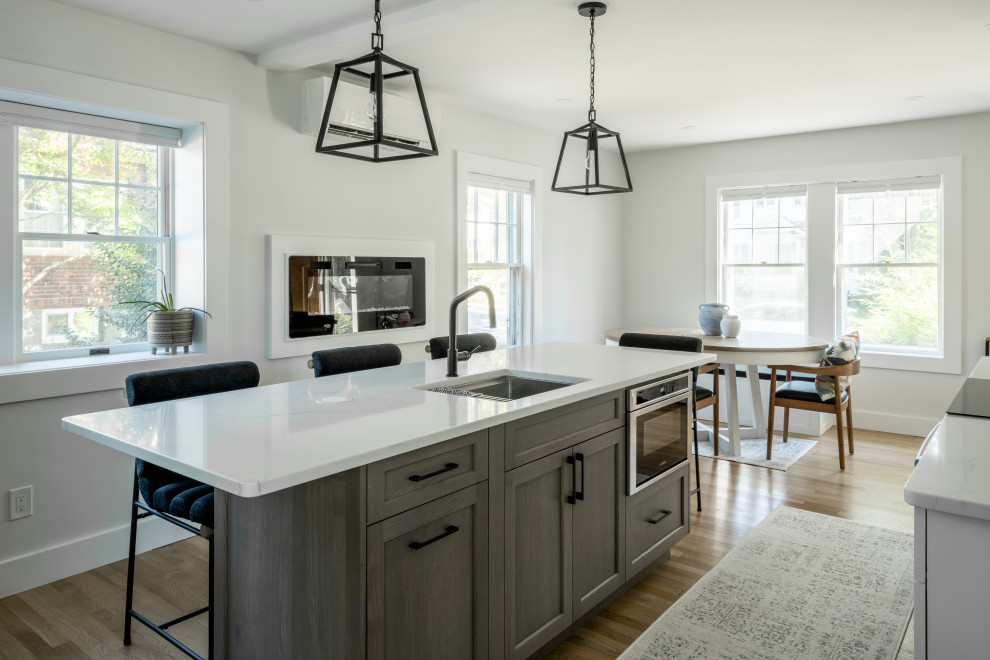 Large trendy l-shaped medium tone wood floor kitchen photo in Boston with an undermount sink, shaker cabinets, gray cabinets, quartz countertops, gray backsplash, cement tile backsplash, stainless steel appliances, an island and white countertops