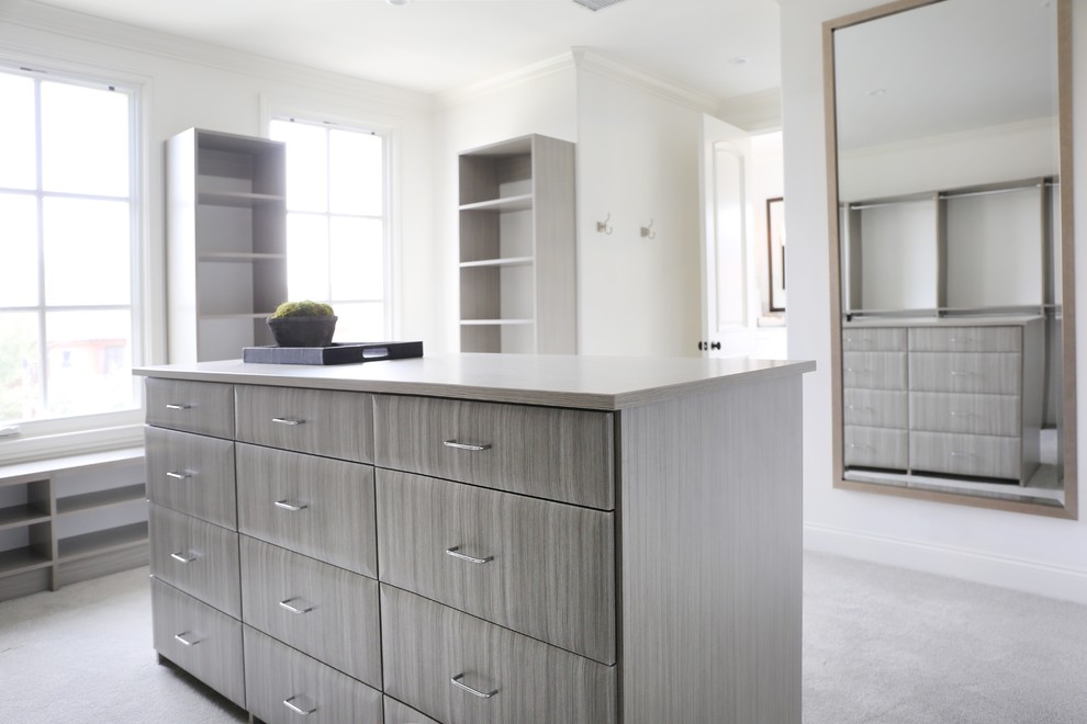 Inspiration for an expansive traditional gender-neutral walk-in wardrobe in Los Angeles with flat-panel cabinets, grey cabinets and carpet.