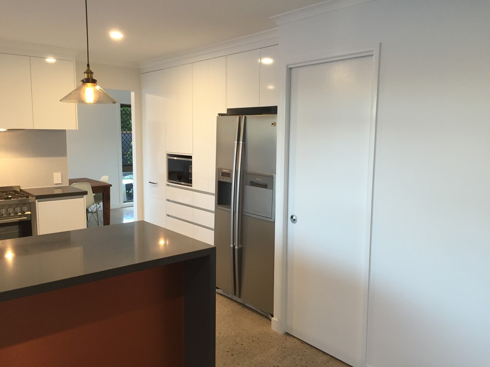 This is an example of a large modern u-shaped kitchen pantry in Sunshine Coast with a submerged sink, open cabinets, white cabinets, engineered stone countertops, grey splashback, ceramic splashback, stainless steel appliances, concrete flooring and no island.