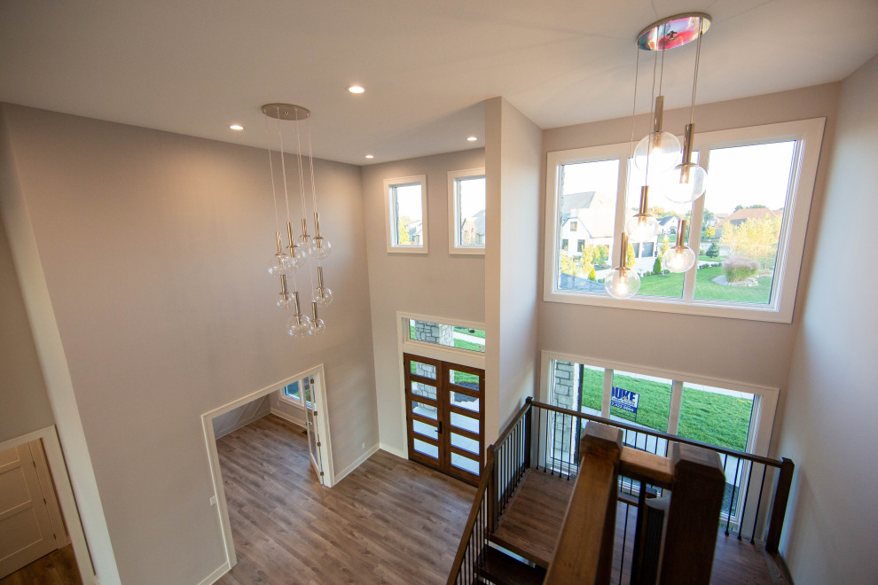 This is an example of a large modern foyer in Indianapolis with beige walls, laminate floors, a double front door, a medium wood front door, brown floor and vaulted.