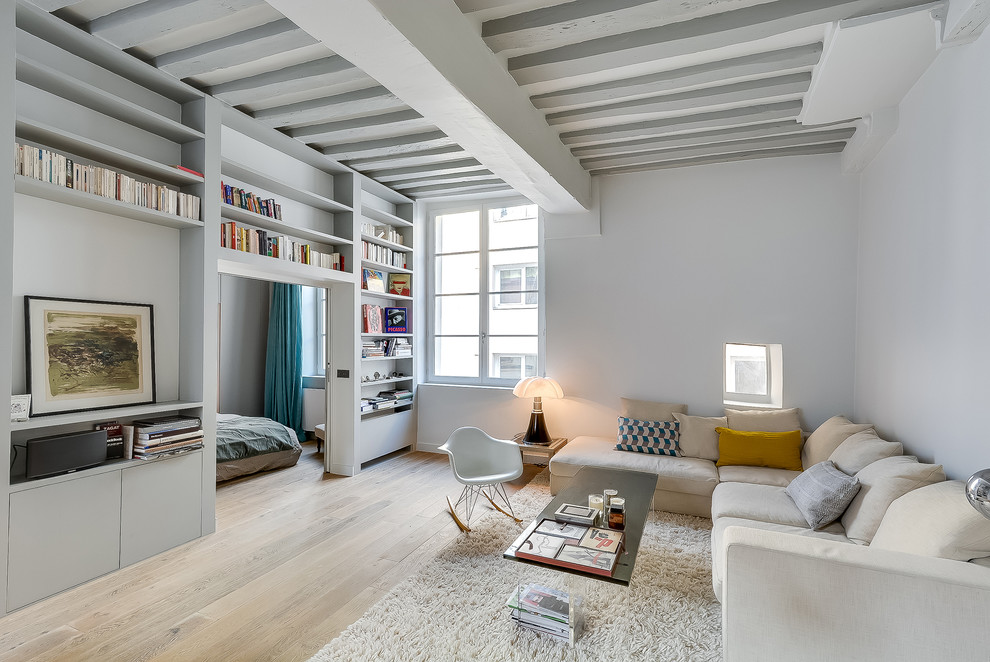 Inspiration for a large scandinavian open concept living room in Paris with white walls, light hardwood floors, a library, no fireplace and no tv.