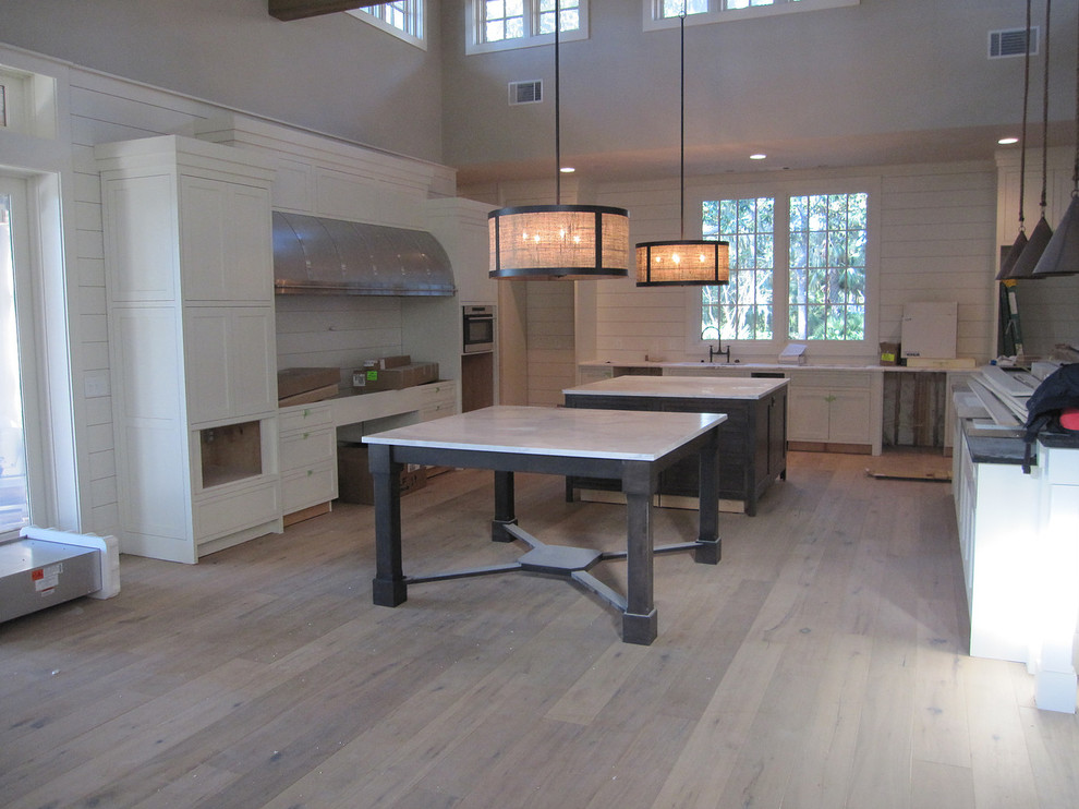 Example of a transitional light wood floor and beige floor kitchen design in Orlando with an undermount sink, shaker cabinets, white cabinets, soapstone countertops, white backsplash, subway tile backsplash, stainless steel appliances and an island