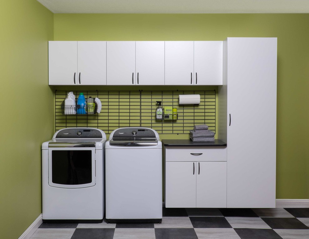 Photo of a mid-sized modern single-wall utility room in Salt Lake City with flat-panel cabinets, white cabinets, solid surface benchtops, green walls, ceramic floors, a side-by-side washer and dryer and black benchtop.