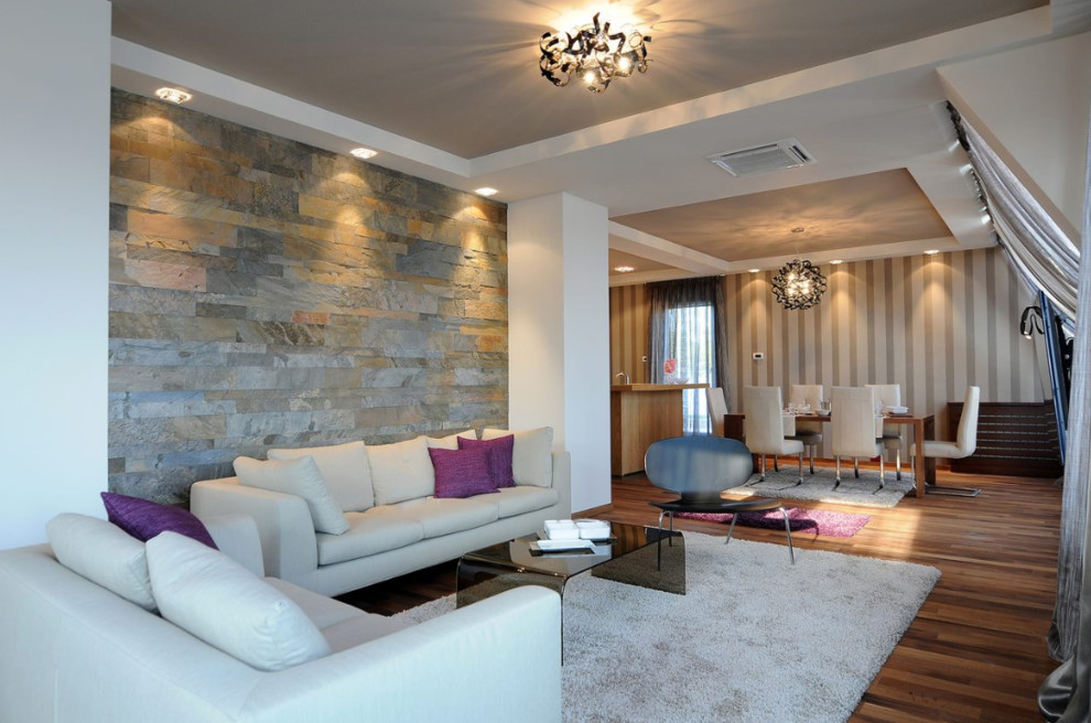 This is an example of a large classic formal open plan living room in New York with grey walls, medium hardwood flooring, a standard fireplace, a metal fireplace surround, a wall mounted tv, brown floors and a drop ceiling.