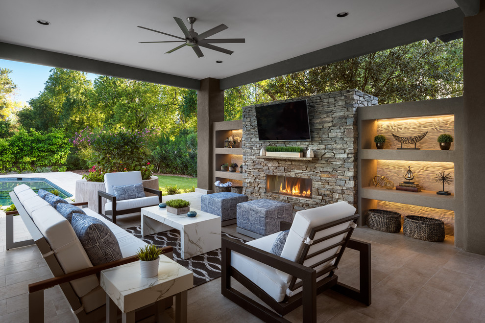 Design ideas for a large contemporary backyard patio in Phoenix with tile, a roof extension and with fireplace.