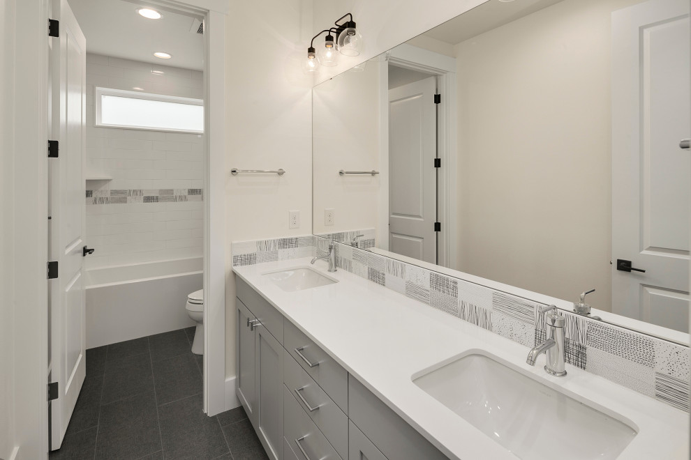 Large country bathroom in Seattle with recessed-panel cabinets, grey cabinets, an alcove bath, a shower/bath combination, a one-piece toilet, white tiles, metro tiles, white walls, cement flooring, a submerged sink, engineered stone worktops, grey floors, an open shower, white worktops, double sinks and a built in vanity unit.