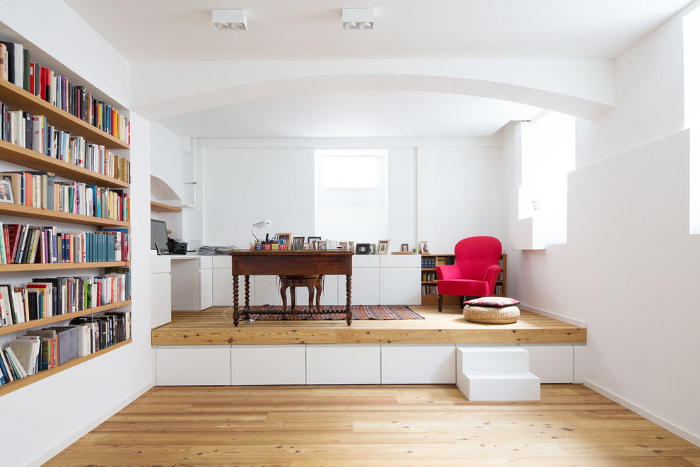 This is an example of a mid-sized contemporary study room in Munich with white walls, light hardwood floors, a freestanding desk, beige floor and no fireplace.