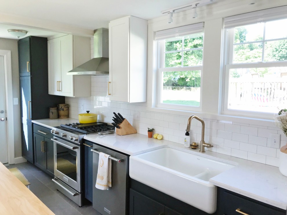 Example of a transitional gray floor kitchen design with a farmhouse sink, quartz countertops and stainless steel appliances