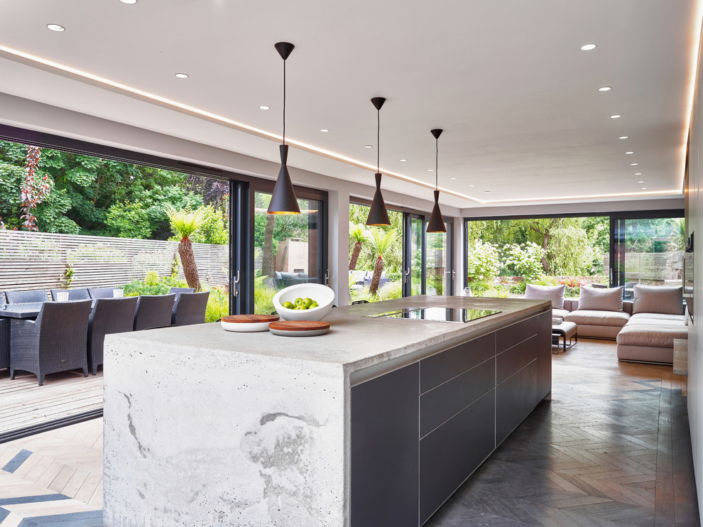 Design ideas for a large contemporary galley open plan kitchen in Devon with flat-panel cabinets, grey cabinets, concrete benchtops, stainless steel appliances, light hardwood floors, with island, multi-coloured floor and grey benchtop.