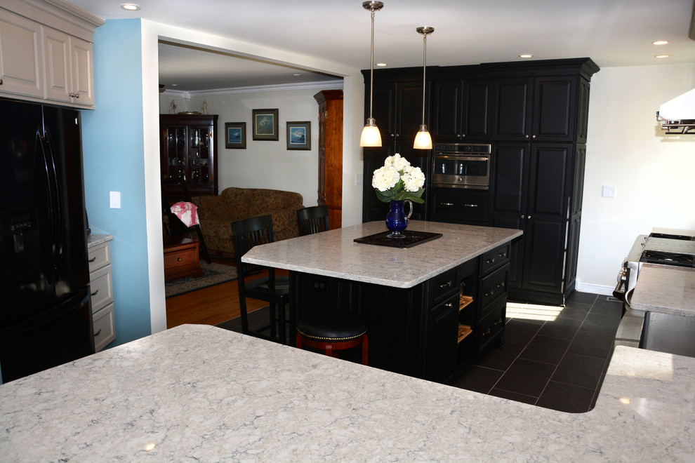 Photo of a large traditional u-shaped separate kitchen in Baltimore with a farmhouse sink, raised-panel cabinets, black cabinets, quartz benchtops, blue splashback, stainless steel appliances, with island, black floor and white benchtop.