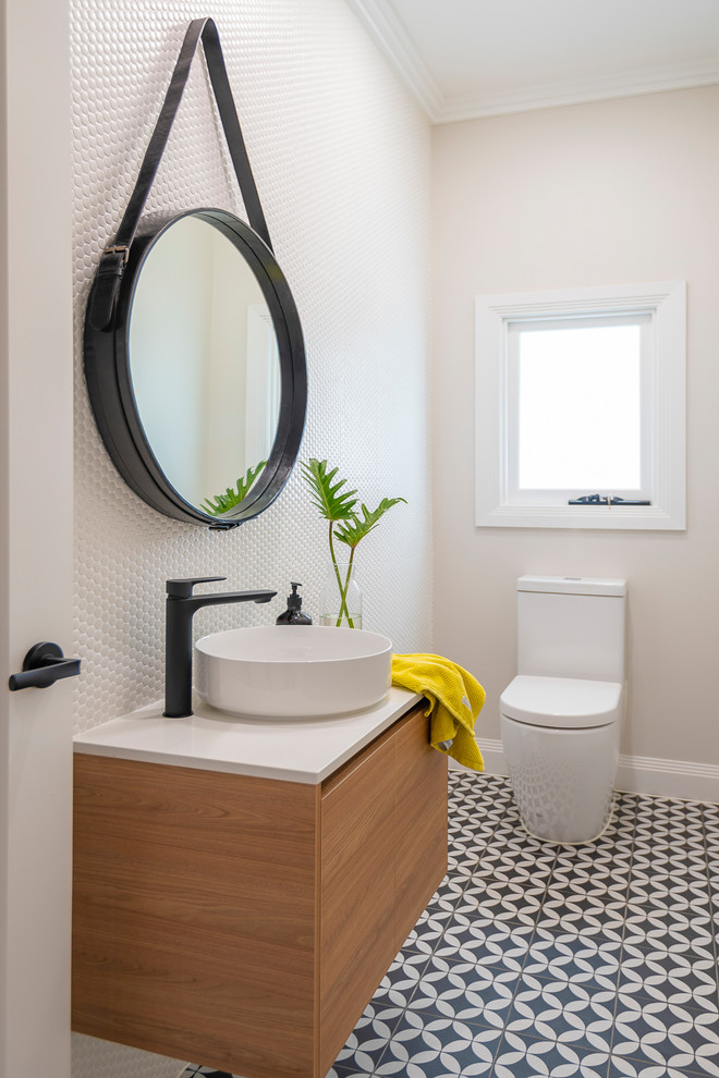 Photo of a mid-sized contemporary powder room in Brisbane with a one-piece toilet, white tile, mosaic tile, white walls, cement tiles, a vessel sink, engineered quartz benchtops, white benchtops, flat-panel cabinets, medium wood cabinets and multi-coloured floor.