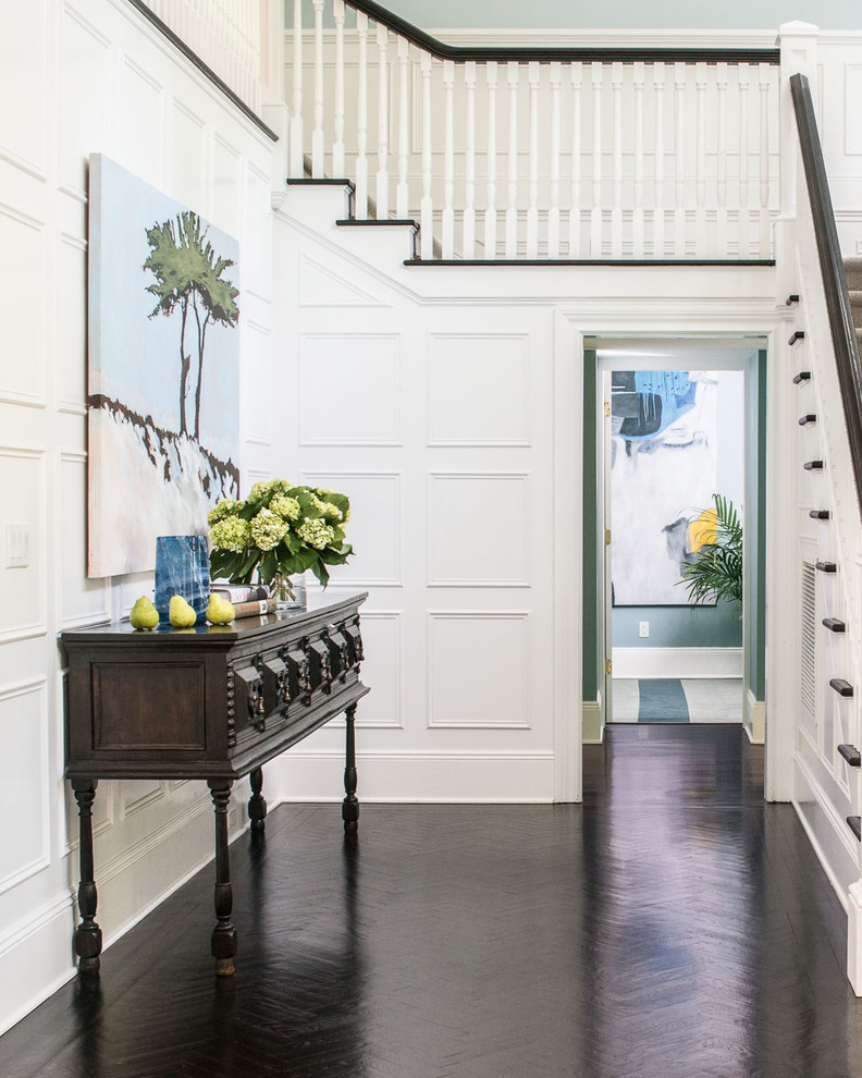 Transitional foyer in New York with white walls and dark hardwood floors.