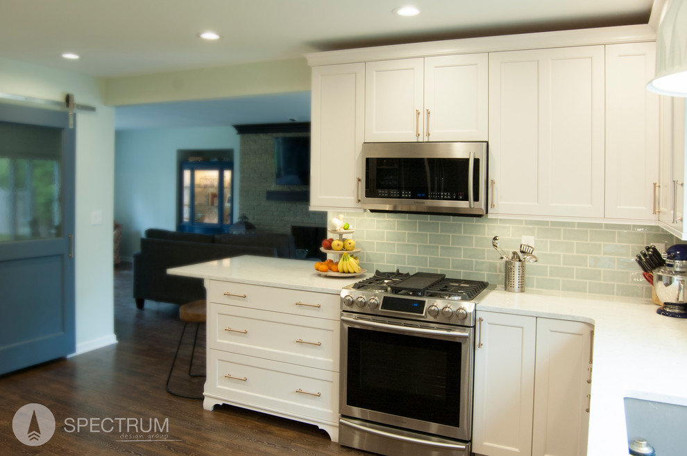 Eat-in kitchen - mid-sized transitional l-shaped dark wood floor eat-in kitchen idea in Chicago with a drop-in sink, raised-panel cabinets, medium tone wood cabinets, solid surface countertops, green backsplash, subway tile backsplash, stainless steel appliances and an island