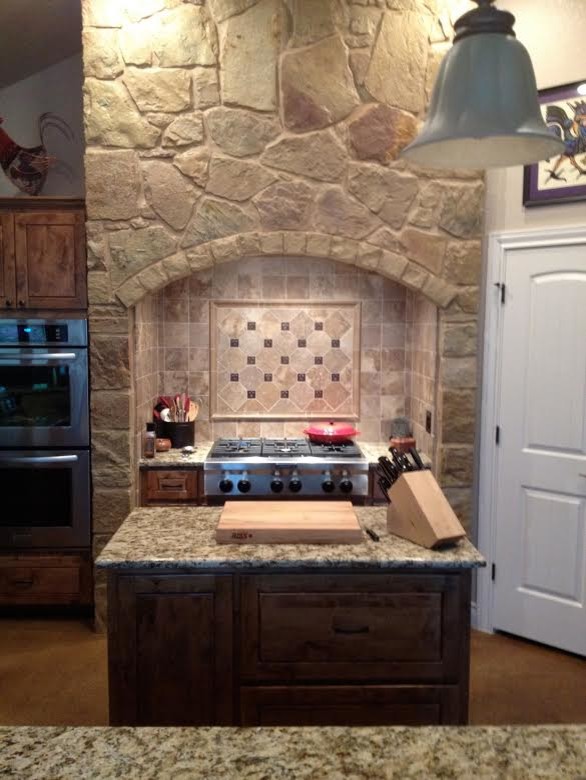Inspiration for a mid-sized rustic l-shaped ceramic tile eat-in kitchen remodel in Austin with an undermount sink, raised-panel cabinets, dark wood cabinets, granite countertops, beige backsplash, ceramic backsplash, stainless steel appliances and an island