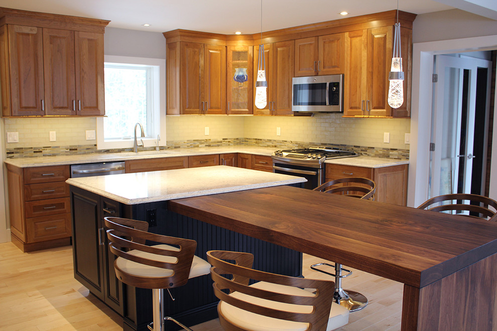 Large transitional u-shaped light wood floor and beige floor open concept kitchen photo in Boston with an undermount sink, raised-panel cabinets, medium tone wood cabinets, quartz countertops, multicolored backsplash, glass tile backsplash, stainless steel appliances, an island and beige countertops