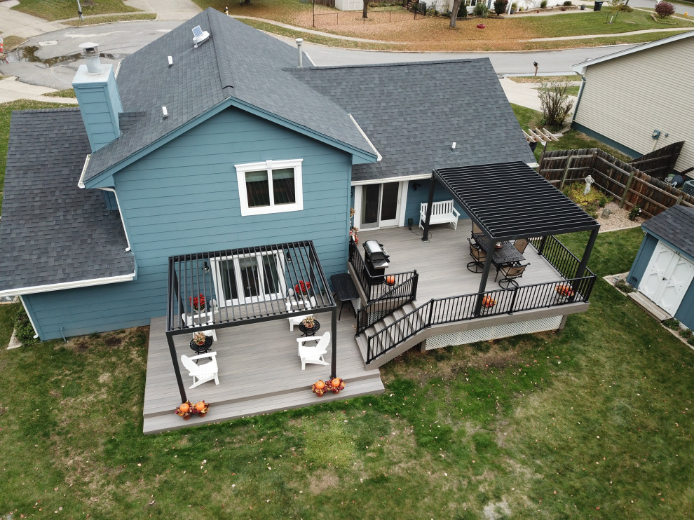 Example of a large backyard ground level metal railing deck design with a pergola
