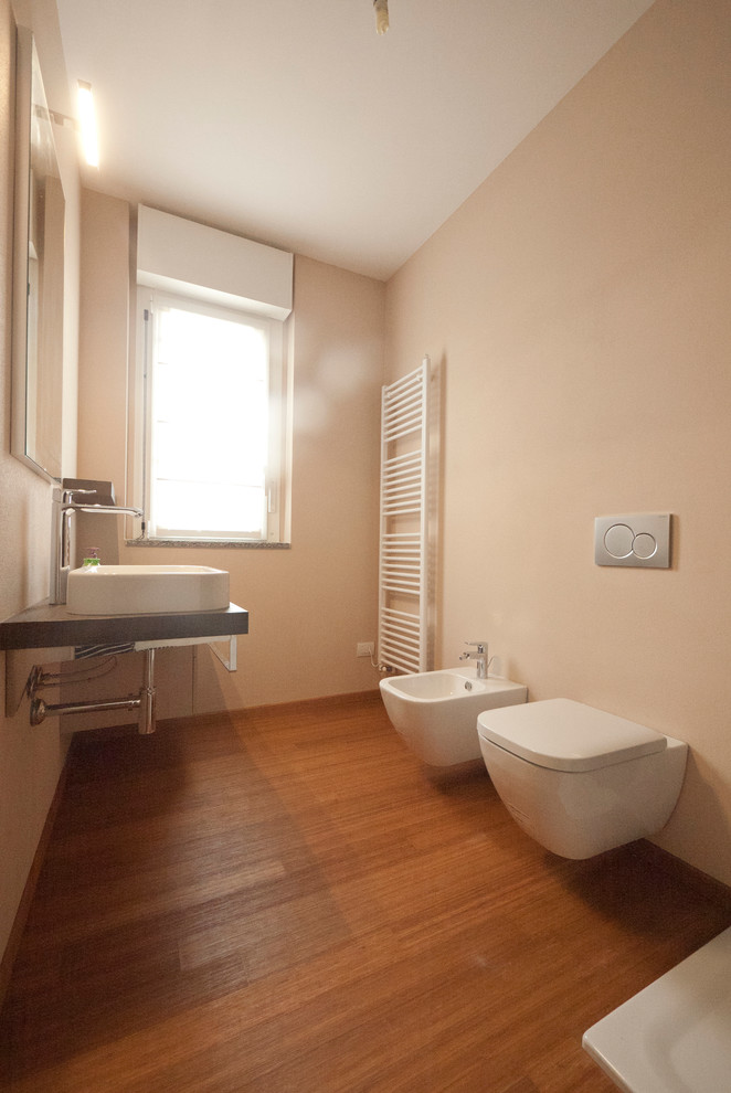 Photo of a mid-sized modern master bathroom in Milan with a console sink, wood benchtops, a corner shower, a two-piece toilet, brown tile, mosaic tile, beige walls and bamboo floors.