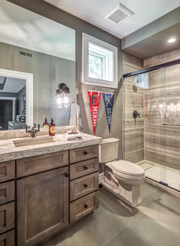 Design ideas for a mid-sized transitional 3/4 bathroom in Cincinnati with recessed-panel cabinets, distressed cabinets, an alcove shower, a two-piece toilet, grey walls, porcelain floors, an undermount sink, granite benchtops, grey floor, a sliding shower screen and beige benchtops.