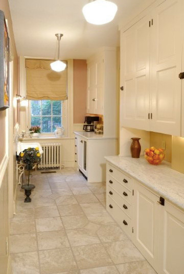 This is an example of a mid-sized country kitchen pantry in Philadelphia with raised-panel cabinets, white cabinets, granite benchtops, beige splashback, stone tile splashback, stainless steel appliances, ceramic floors, with island and grey floor.