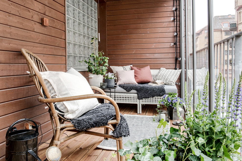 Design ideas for a mid-sized scandinavian balcony in Gothenburg with a roof extension and glass railing.