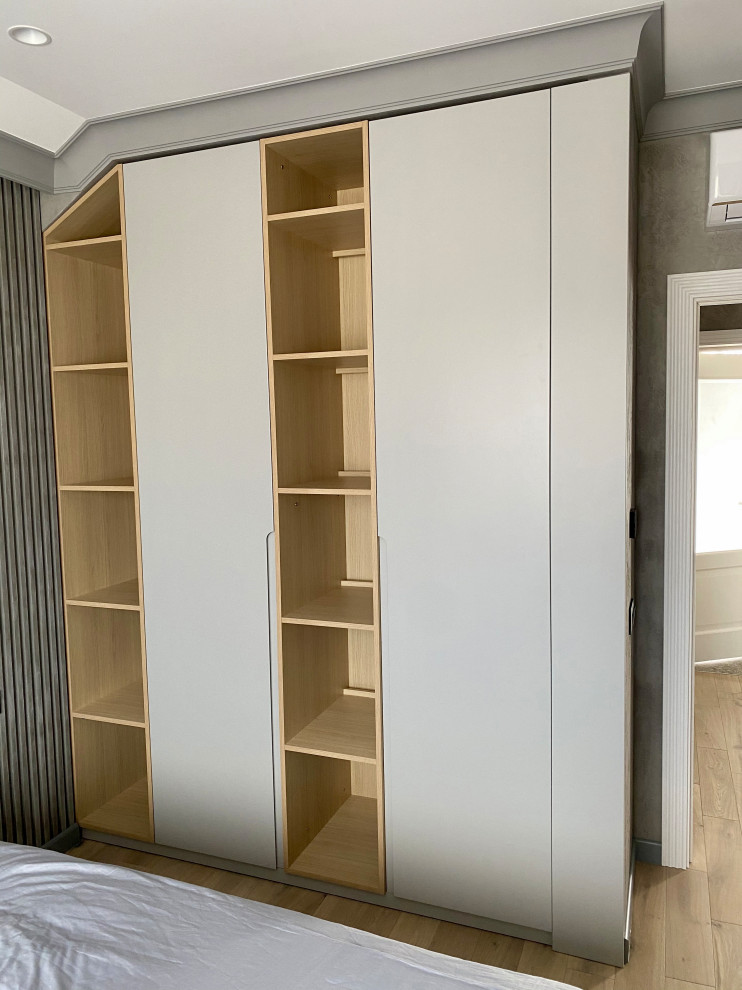 This is an example of a mid-sized gender-neutral storage and wardrobe in Hertfordshire with flat-panel cabinets, grey cabinets, laminate floors, orange floor and exposed beam.