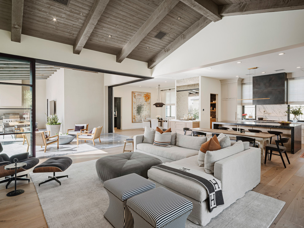 Inspiration for a modern open concept living room in Phoenix with white walls, light hardwood floors, a ribbon fireplace, a plaster fireplace surround, a wall-mounted tv, beige floor and exposed beam.