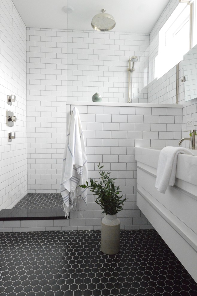 Mid-sized modern 3/4 bathroom in New York with flat-panel cabinets, white cabinets, an open shower, a one-piece toilet, white tile, subway tile, black walls, ceramic floors, an integrated sink, solid surface benchtops, black floor, an open shower and white benchtops.