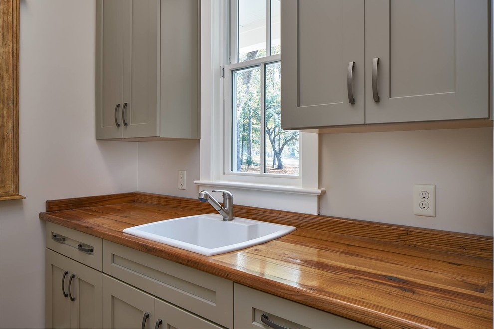 Mid-sized galley dedicated laundry room in Atlanta with a drop-in sink, shaker cabinets, beige cabinets, wood benchtops, beige walls, light hardwood floors and a side-by-side washer and dryer.