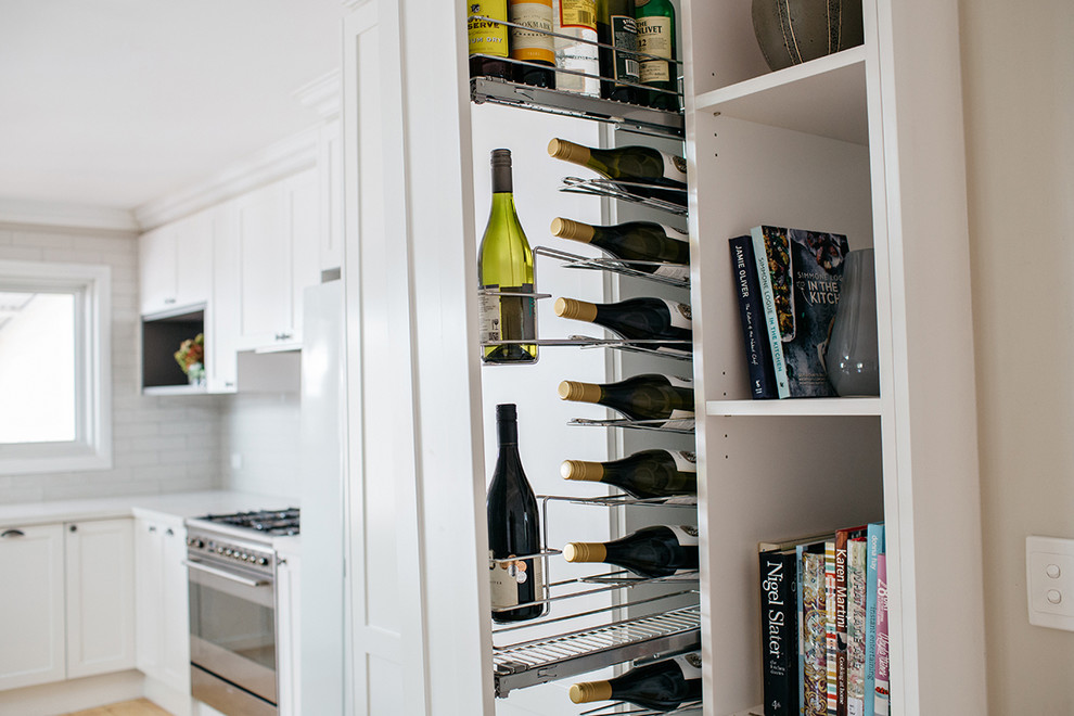Inspiration for a large transitional open plan kitchen in Melbourne with a farmhouse sink, shaker cabinets, white cabinets, quartz benchtops, white splashback, subway tile splashback, stainless steel appliances, light hardwood floors and with island.