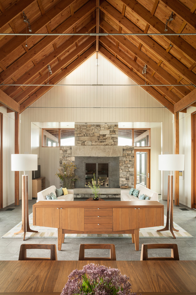 Photo of an expansive contemporary open concept living room in Portland Maine with white walls, a standard fireplace, a stone fireplace surround and a concealed tv.