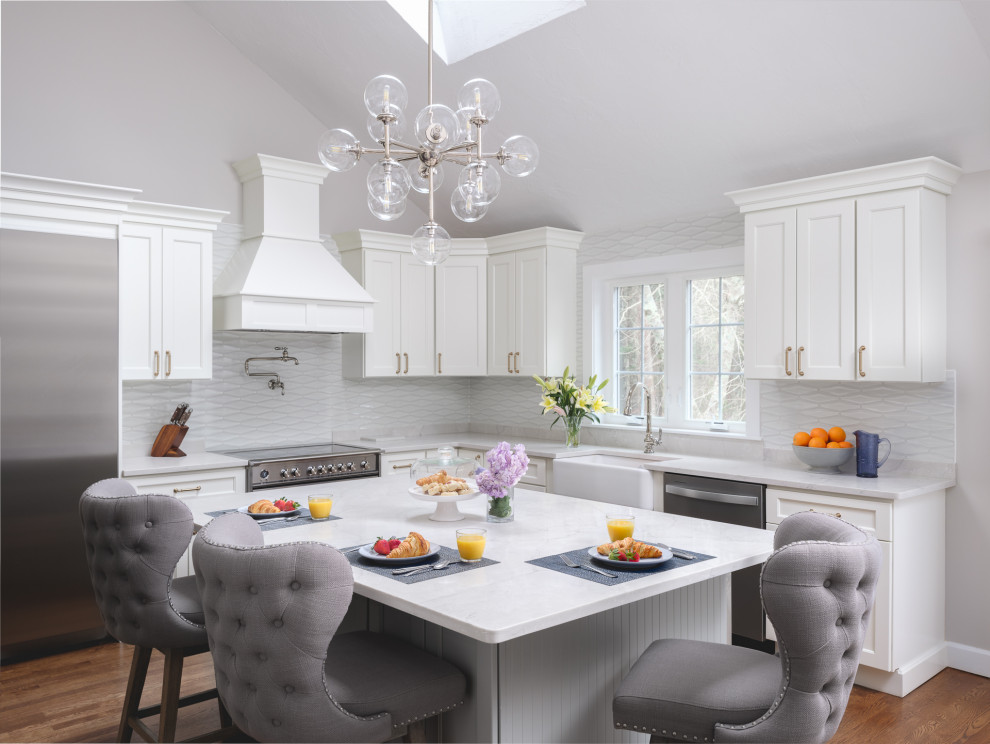 Large transitional l-shaped medium tone wood floor and brown floor kitchen photo in Boston with white cabinets, white backsplash, an island and white countertops
