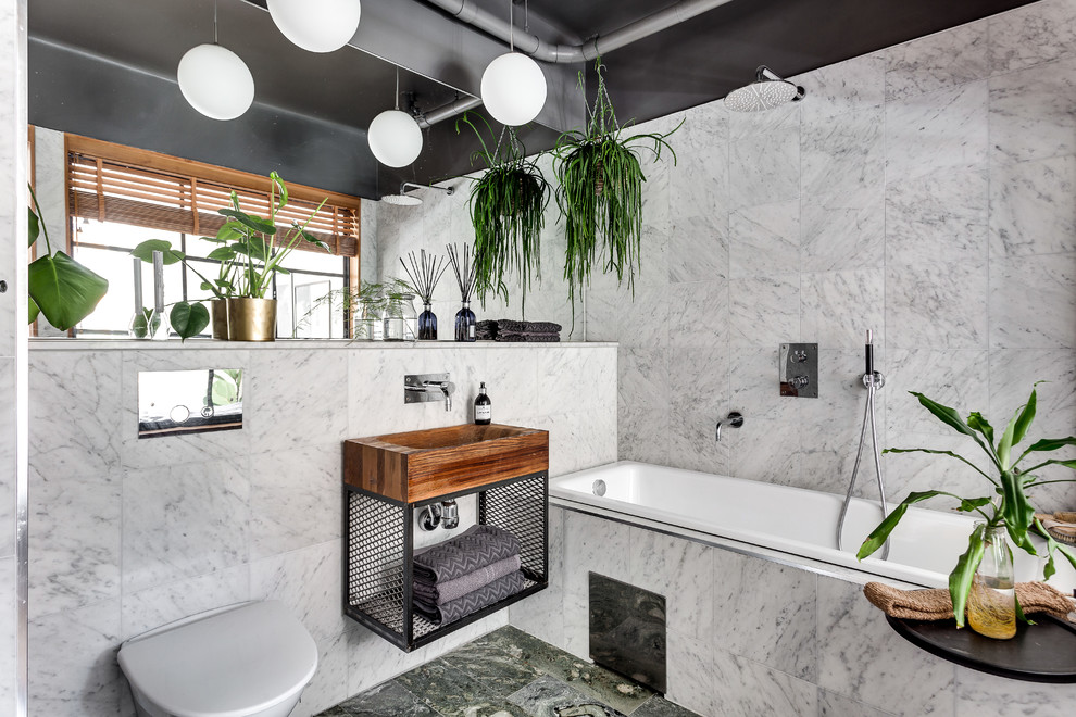 Design ideas for a mid-sized contemporary master bathroom in Stockholm with open cabinets, a drop-in tub, a shower/bathtub combo, a wall-mount toilet, white tile, medium wood cabinets, grey walls, marble floors and a vessel sink.