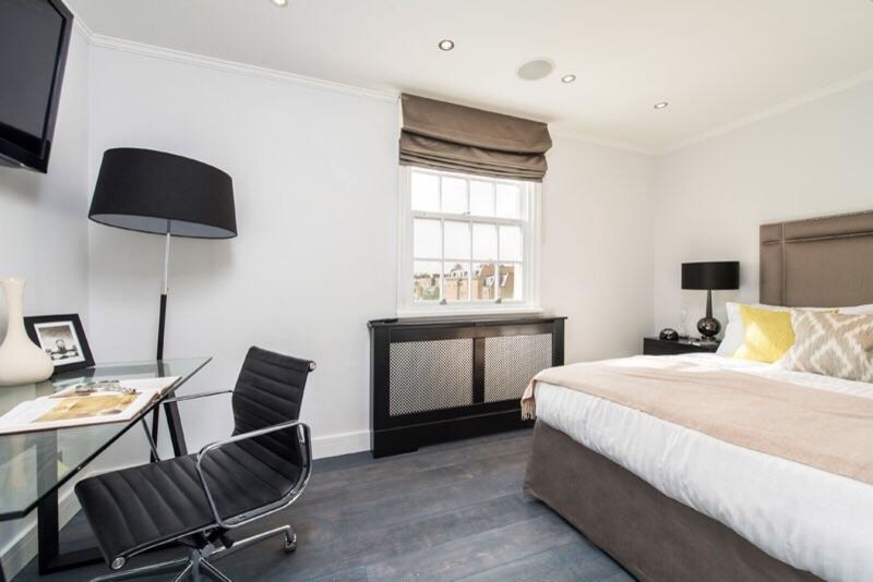 Design ideas for a mid-sized modern guest bedroom in London with white walls, dark hardwood floors and no fireplace.