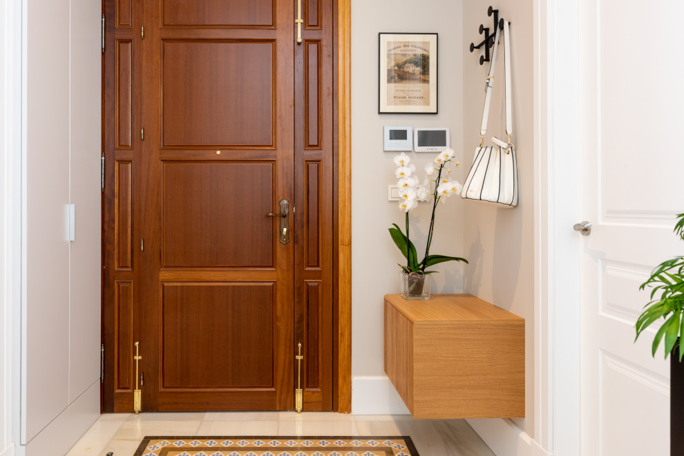 Foto de puerta principal contemporánea con paredes beige, suelo de mármol, puerta simple, puerta de madera en tonos medios y suelo blanco