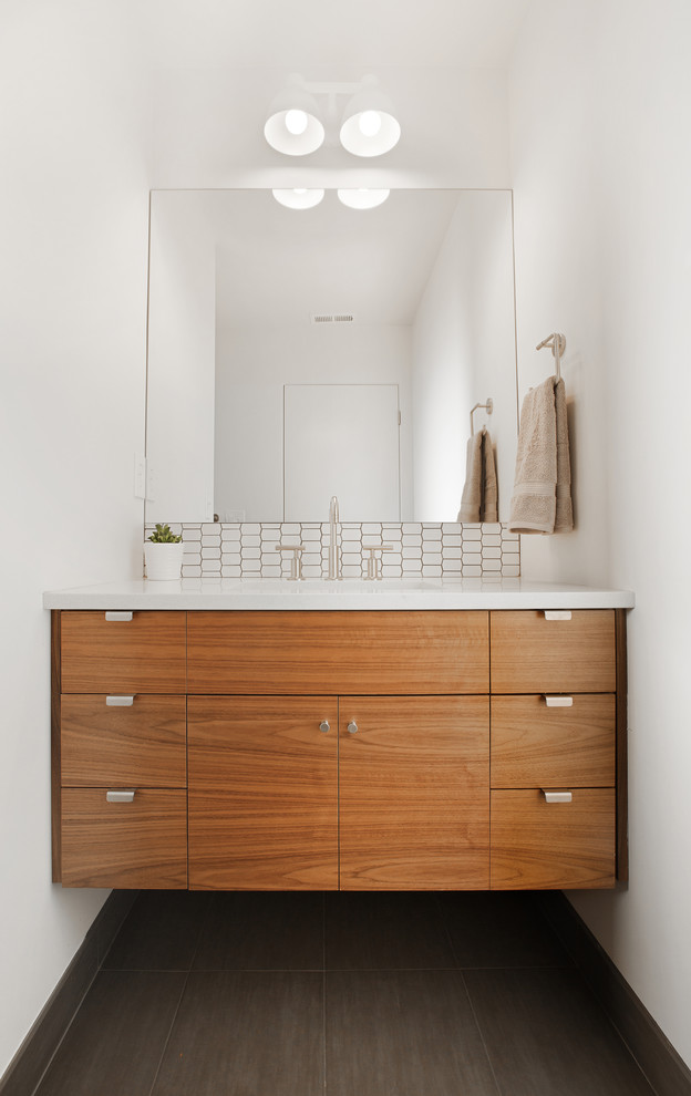 This is an example of a contemporary powder room in Portland with flat-panel cabinets, medium wood cabinets, white walls and brown floor.