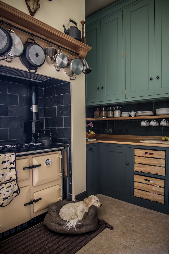 Photo of a small contemporary l-shaped eat-in kitchen in Gloucestershire with a drop-in sink, shaker cabinets, green cabinets, wood benchtops, black splashback, stone tile splashback, coloured appliances, limestone floors and no island.