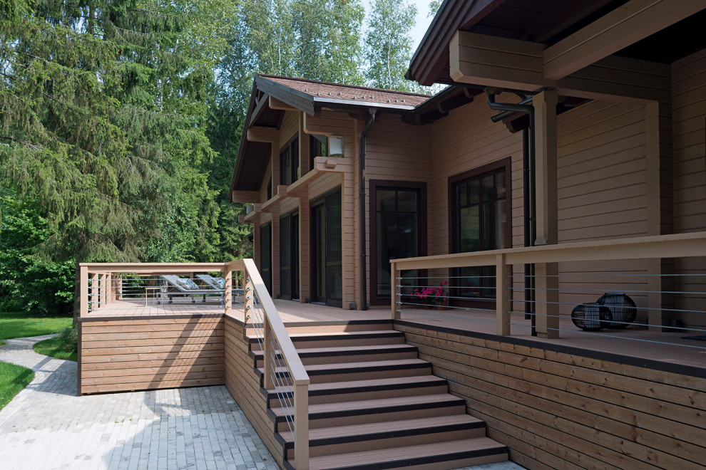This is an example of a mid-sized country courtyard and ground level deck in Moscow with a roof extension and wood railing.