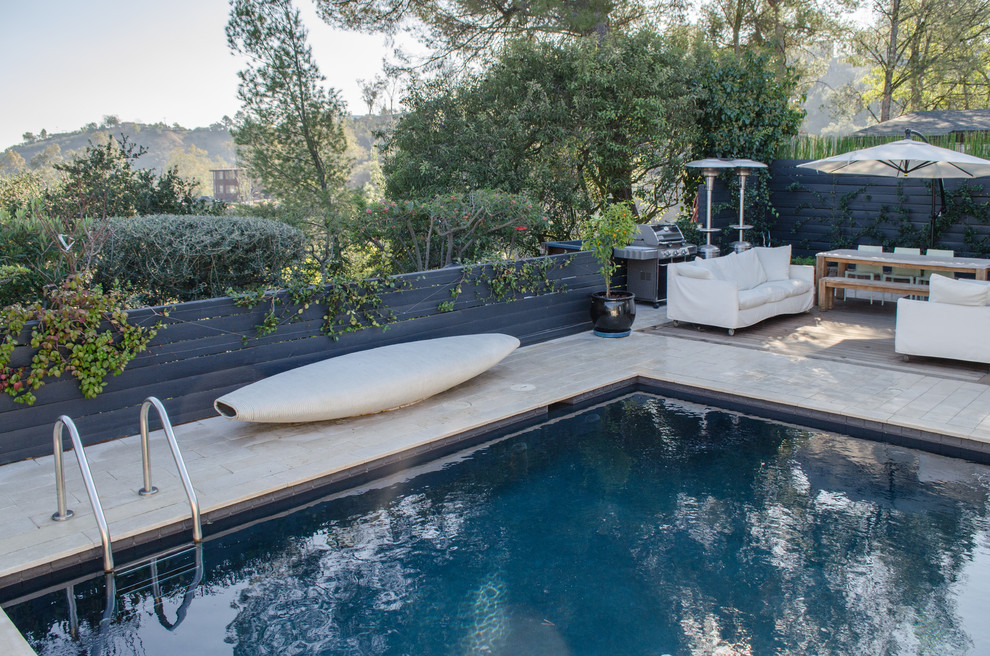 Photo of a small backyard custom-shaped pool in Los Angeles with tile.