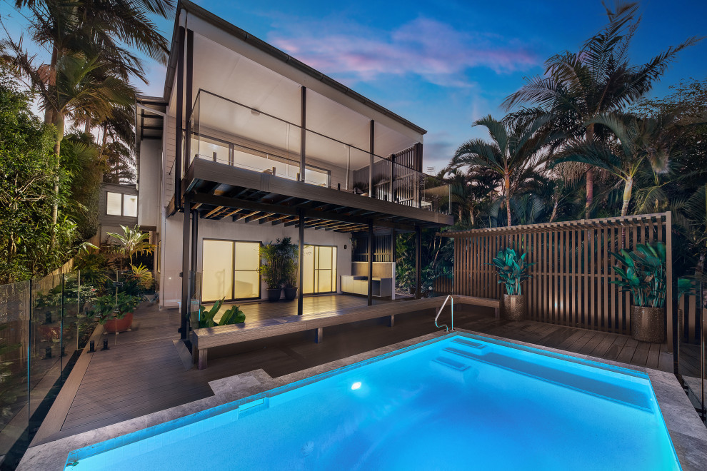 Réalisation d'une piscine arrière marine de taille moyenne et rectangle avec une terrasse en bois.