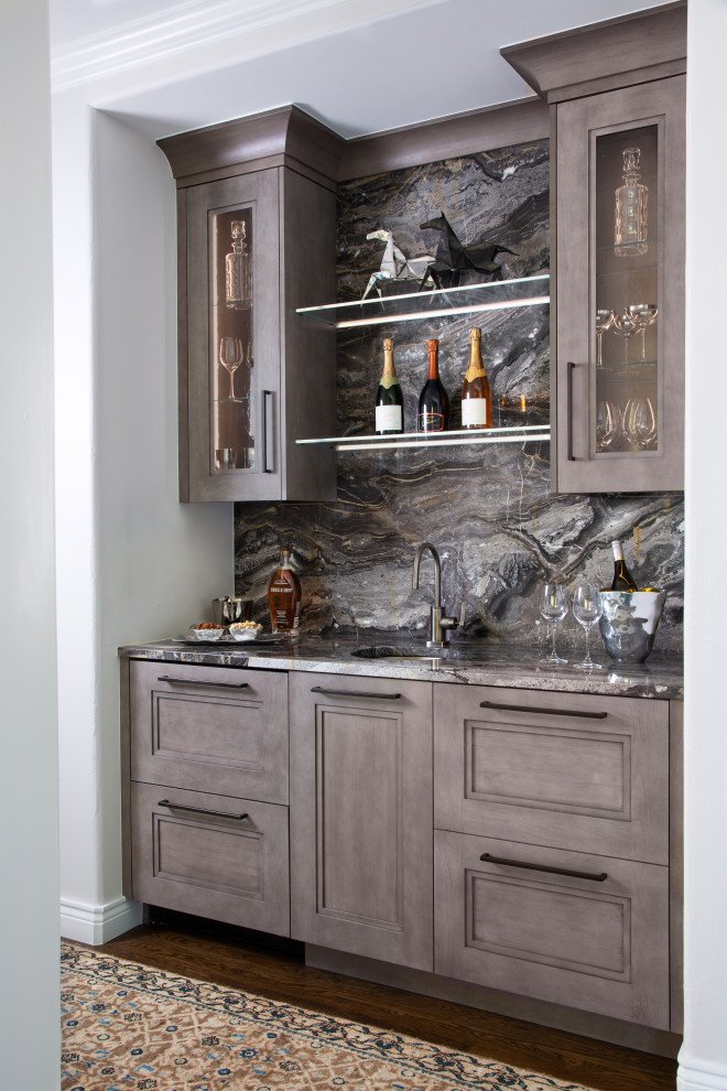 Inspiration for a small arts and crafts single-wall wet bar in Denver with an undermount sink, glass-front cabinets, grey cabinets, grey splashback, medium hardwood floors, brown floor and grey benchtop.