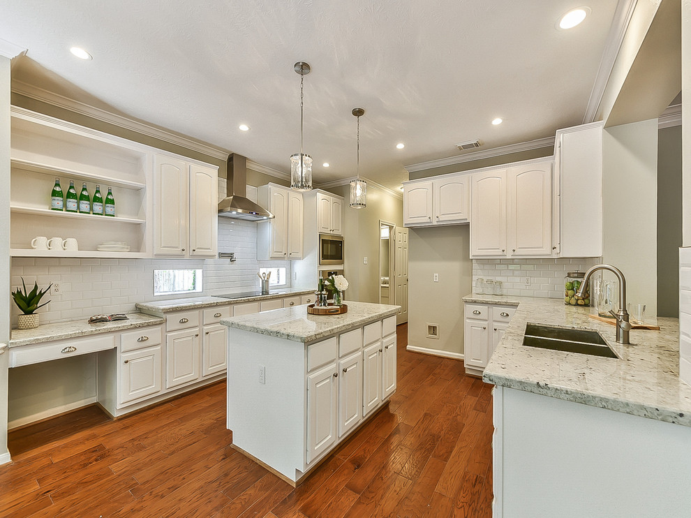 Inspiration for a mid-sized transitional u-shaped medium tone wood floor and orange floor eat-in kitchen remodel in Houston with an undermount sink, white cabinets, granite countertops, white backsplash, subway tile backsplash, stainless steel appliances, an island, white countertops and raised-panel cabinets
