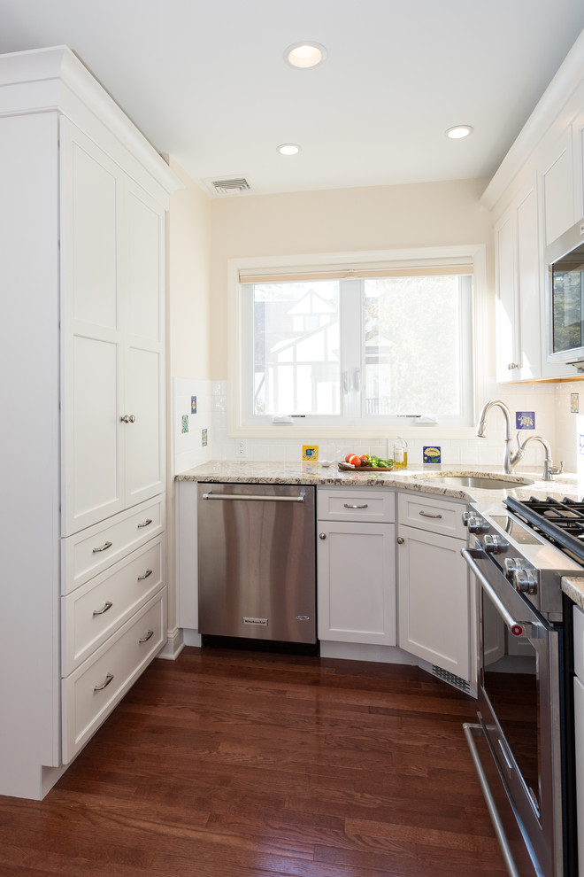 Photo of a small transitional u-shaped eat-in kitchen in New York with an undermount sink, shaker cabinets, white cabinets, granite benchtops, white splashback, ceramic splashback, stainless steel appliances, medium hardwood floors and no island.