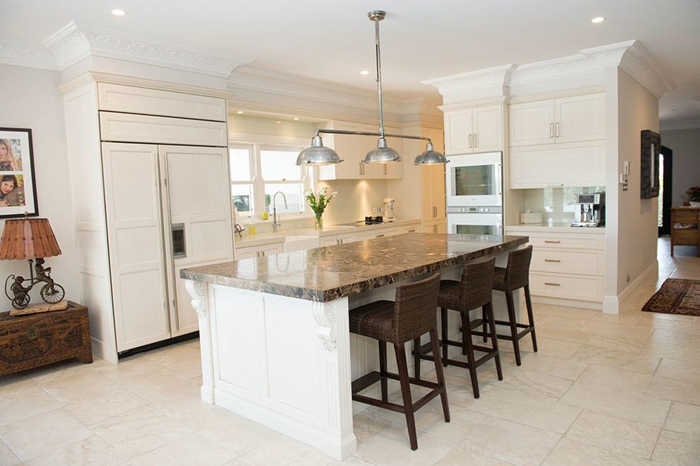 Large traditional l-shaped eat-in kitchen in Sydney with beige cabinets, a farmhouse sink, shaker cabinets, quartz benchtops, beige splashback, glass sheet splashback, stainless steel appliances, with island and travertine floors.