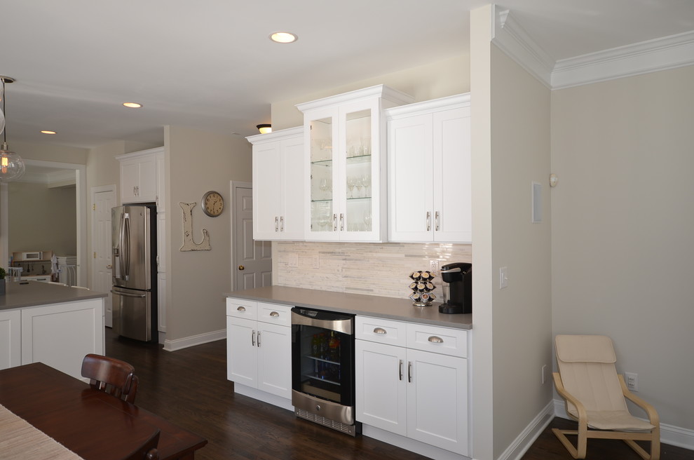 This is an example of a mid-sized country kitchen in Charlotte with a farmhouse sink, shaker cabinets, white cabinets, quartz benchtops, grey splashback, mosaic tile splashback, stainless steel appliances, dark hardwood floors and with island.