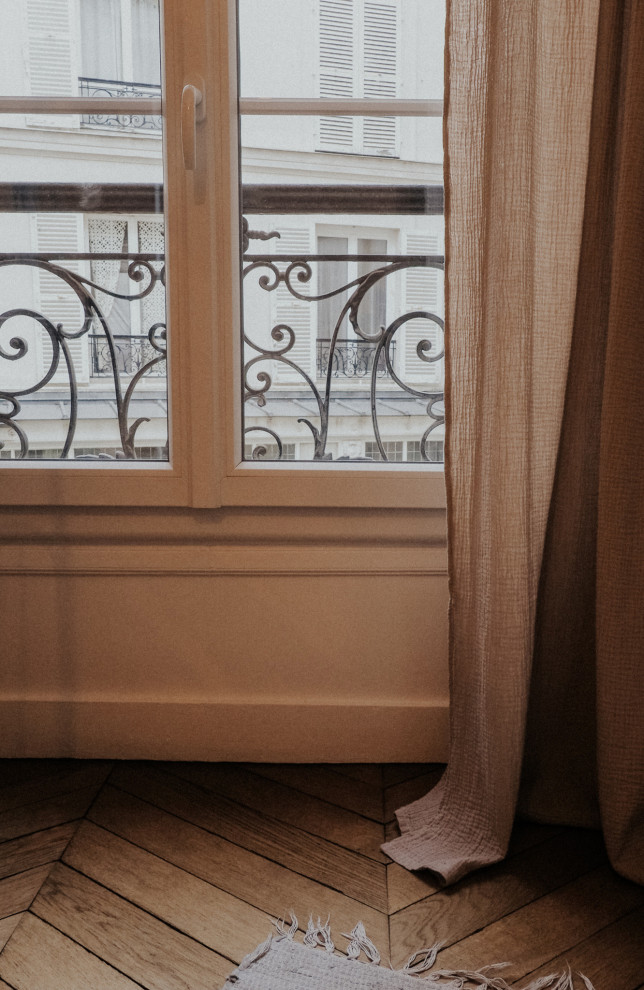 Exemple d'une chambre parentale haussmannienne tendance de taille moyenne avec un mur blanc, parquet clair, une cheminée standard, un manteau de cheminée en pierre et un sol marron.