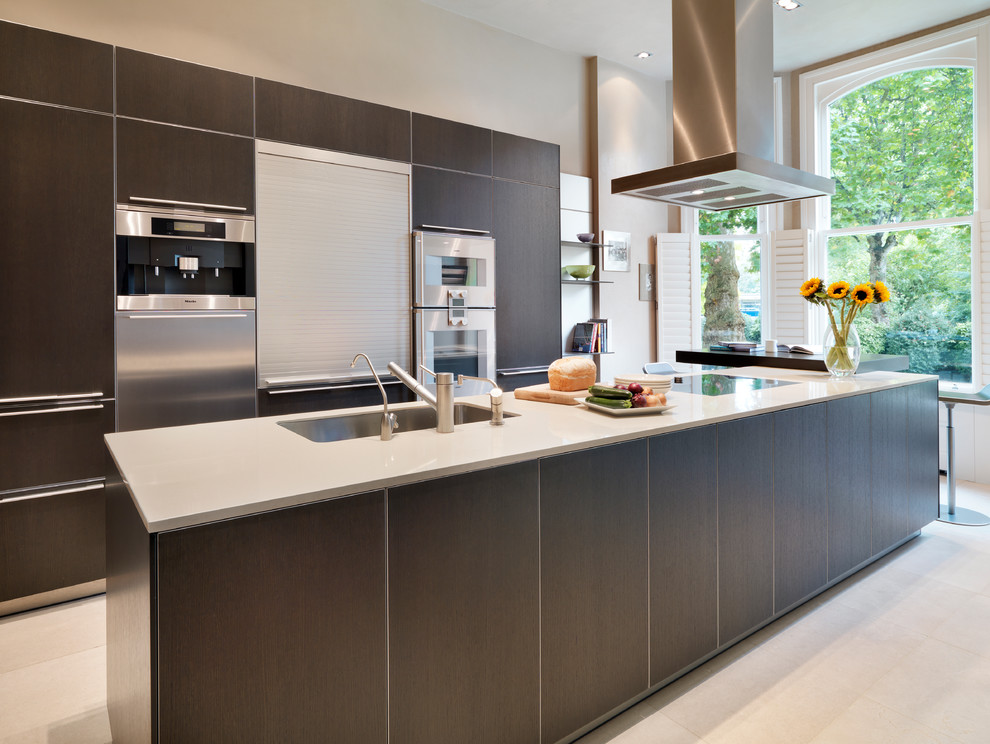 This is an example of a contemporary kitchen in London with an undermount sink, flat-panel cabinets, dark wood cabinets, stainless steel appliances and with island.
