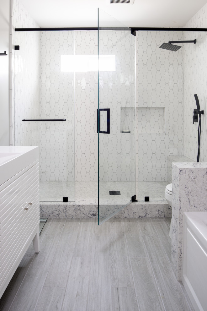 This is an example of a mid-sized modern master bathroom in Santa Barbara with flat-panel cabinets, white cabinets, an alcove tub, an alcove shower, a one-piece toilet, black and white tile, subway tile, white walls, light hardwood floors, a console sink, engineered quartz benchtops, grey floor, a sliding shower screen, white benchtops, a shower seat, a single vanity and a freestanding vanity.